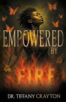 Paperback book "Empowered by Fire" by Cocoon to Wings Publishing displayed on a wooden table with a cozy background.
