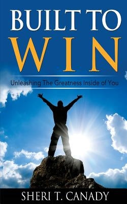 Paperback book "Built To Win: Unleashing The Greatness Inside Of You" on a wooden surface with a blurred background.