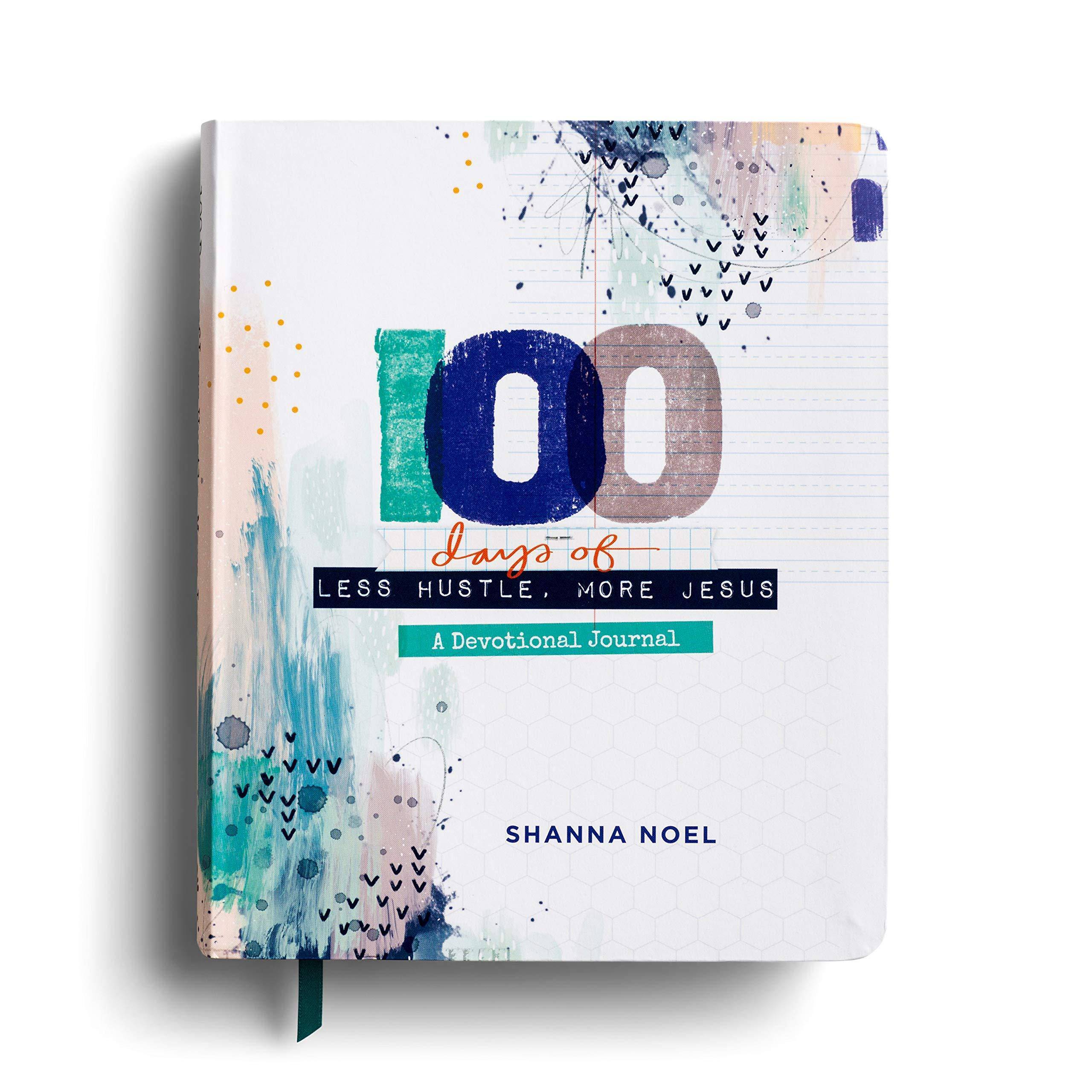 Open devotional journal titled "100 Days of Less Hustle, More Jesus" by Shanna Noel, featuring handwritten-style religious illustrations.
