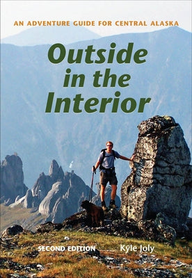Paperback book titled "Outside in the Interior," adventure guide for Central Alaska, published by University of Alaska Press.